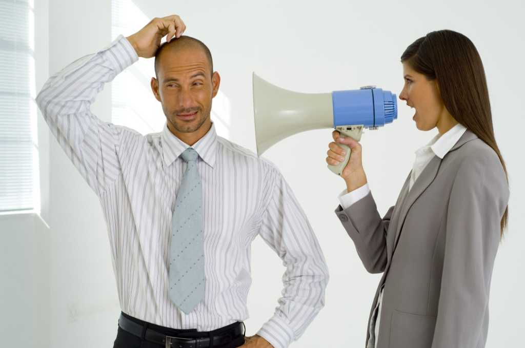 Woman executive yelling into megaphone at man.
